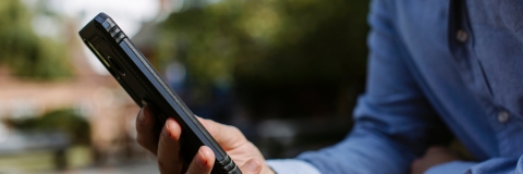 Man's hand holding mobile phone, resting on a table