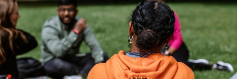 Three students sat down on grassy field 