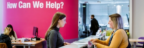 Female student standing at careers and employability help desk