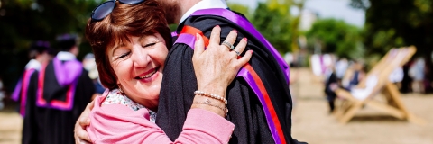 Happy mother hugging student