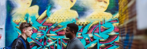 Two students talking in front of graphic painted on wall