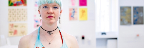 A woman with blue hair standing in front of artwork