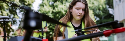 Student kneels next to the drone taking readings on touchpad outside Technology Facilities
Note: The drone is only currently operable by technicians.