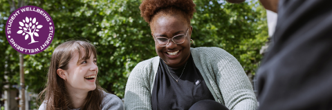 Student Wellbeing hero image showing two students sitting on steps and laughing