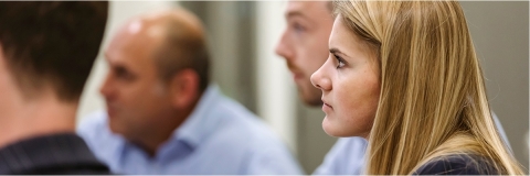 Female in suit watches speaker during career presentation