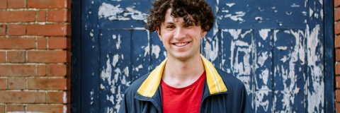 Student smiling in blue jacket with red shirt
