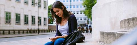 Student using mobile phone while sitting on steps outside the Park building