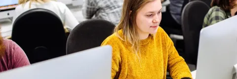 Student in computer suite in yellow jumper
