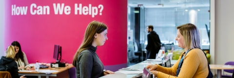 Female student standing at careers and employability help desk