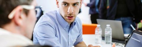 Man talking to another man over papers