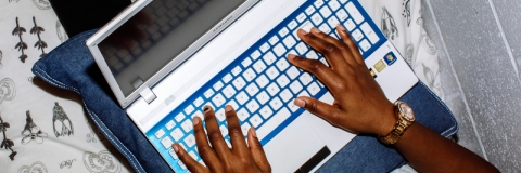 Student using laptop to complete university work in halls bedroom