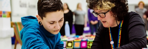 Staff member helping student crochet at feel good festival
