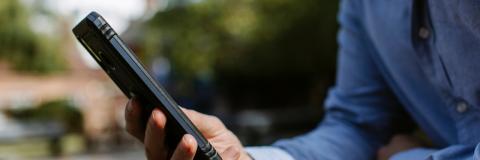 Man's hand holding mobile phone, resting on a table