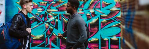 Two students talking in front of graphic painted on wall