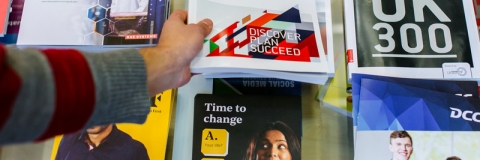 Career guidance books and leaflets on a desk with a person's hand picking one up