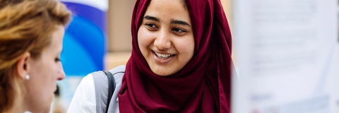 Student in hijab has a conversation with peer at research conference