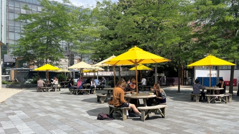 Students eating lunch outside under tables with yellow umbrellas