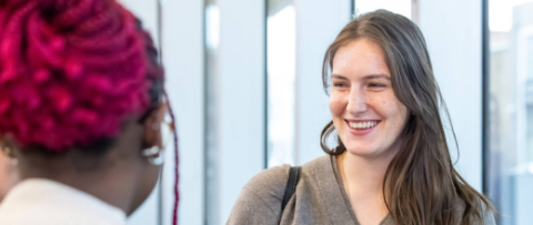 A female student smiling and talking to their friend
