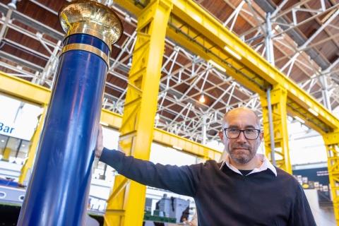 Carlos Ausejo stands onboard a steamship and beside its stack/funnel in Boathouse 4, Portsmouth Historic Quarter