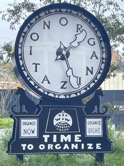 A clock sculpture. In place of numbers are the letters to spell out organization