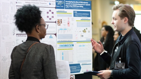 Two postgraduate research students discussing a research poster