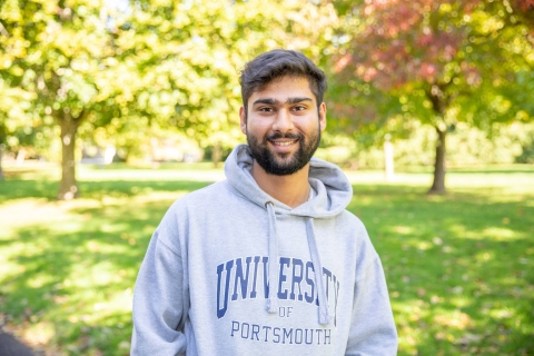 Male student in University of Portsmouth hoodie student outside