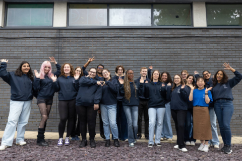A group of university students looking happy and celebratory, dressed in uniform