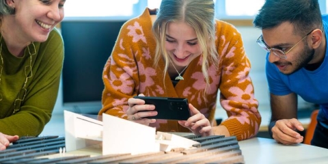 Three students looking at image on a phone screen