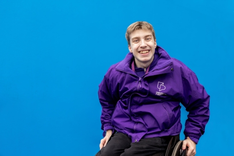University ambassador standing and smiling against blue background