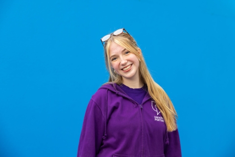 University ambassador standing and smiling against blue background