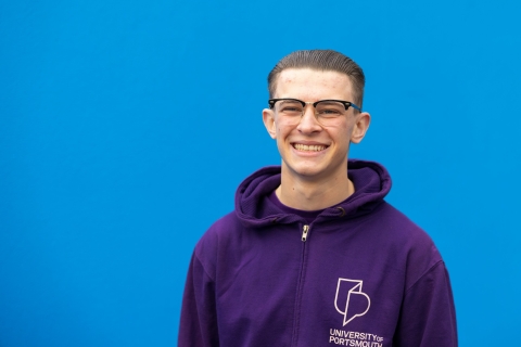 University ambassador standing and smiling against blue background
