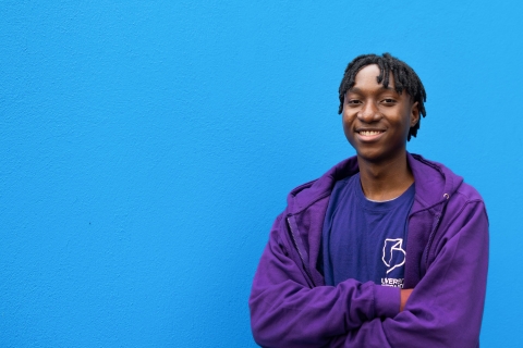 University ambassador standing and smiling against blue background