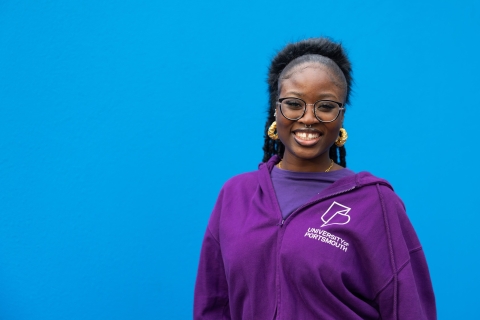 University ambassador standing and smiling against blue background