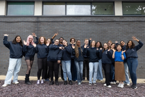 A group of university students looking happy and celebratory, dressed in uniform