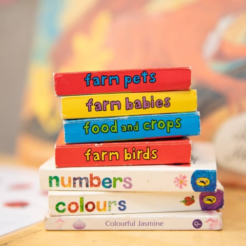 Seven small colourful children's books stacked upon one and other