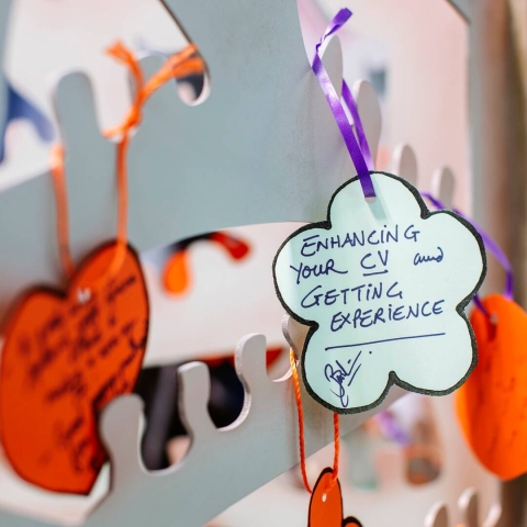A metal tree with hand written colourful tags hanging off of it. The main tag says 'Enhancing your CV and getting experience'