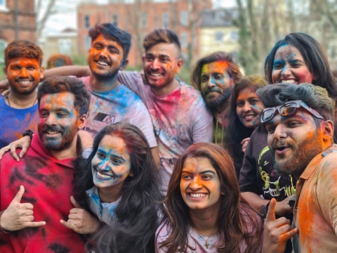 Students celebrating Holi covered in different coloured powder paint