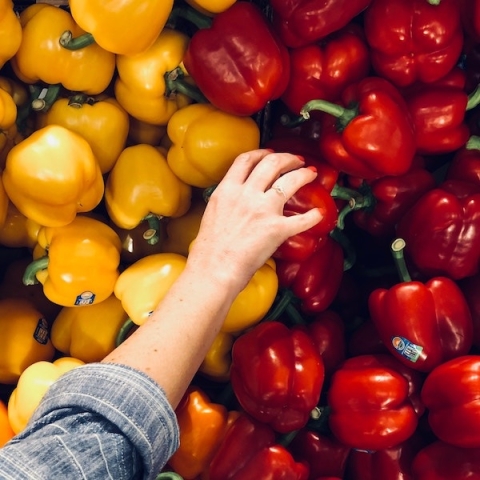 A hand reaching for a pepper in a shop