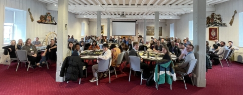 The in-person induction postgraduate students sat at round tables in a big room, posing for a group photo