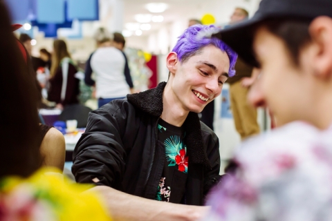 Student with purple hair smiles with friends at the feel good festival