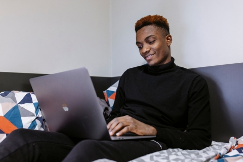 Male student sitting on a bed in halls