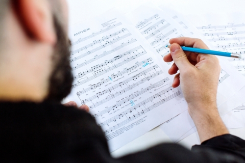 Person marking sheet music with light blue pencil
