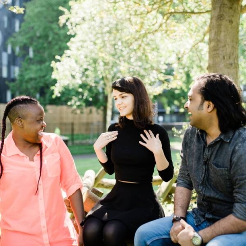Group of three individuals sitting on bench in park