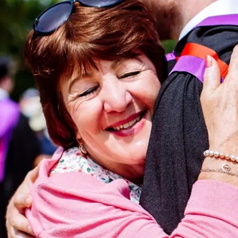 Happy mother hugging student