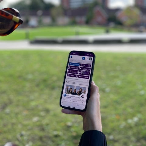 Student holding a mobile device with new MyPort homepage displaying on screen