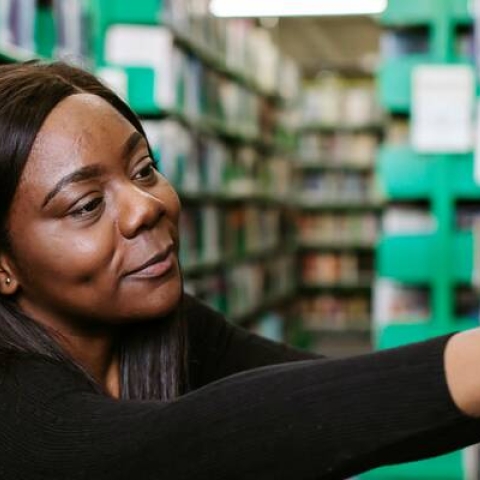 Student reaching for library book