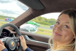 Daisy seated behind the wheel of a Porsche on test track