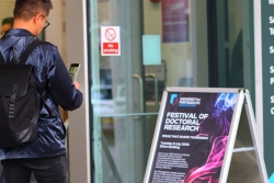 A festival delegate reading the festival sign board outside Eldon Building