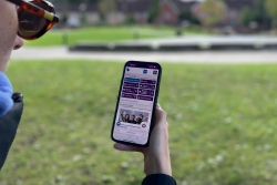 Student holding a mobile device with new MyPort homepage displaying on screen