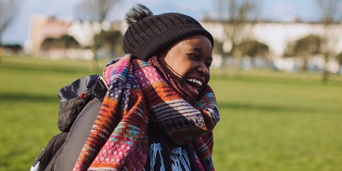 Student smiling in sun wearing winter scarf and hat